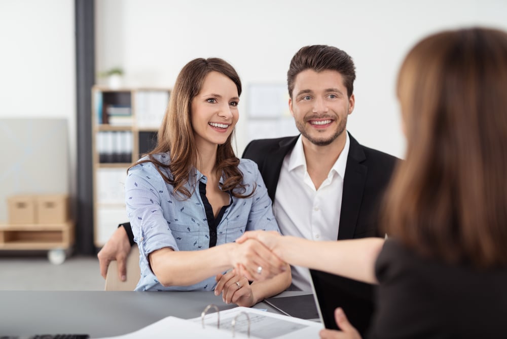 Happy Young Professional Couple Shaking Hands with a Real Estate Agent After Some Business Discussions Inside the Office. Happy Young Professional Couple Shaking Hands with a Real Estate Agent After Some Business Discussions Inside the Office.